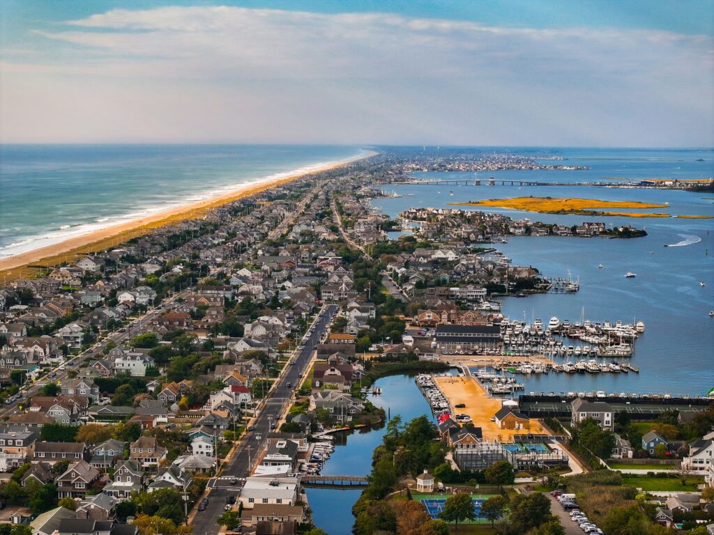 Aerial view of Bay Head, NJ, showcasing the narrow barrier island community with oceanfront homes along the Atlantic beach and bayfront properties with marinas along the calm Barnegat Bay