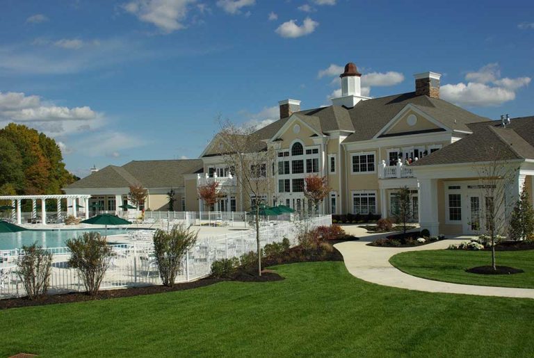 Elegant clubhouse and outdoor pool area surrounded by manicured landscaping in a 55+ active adult community in New Jersey