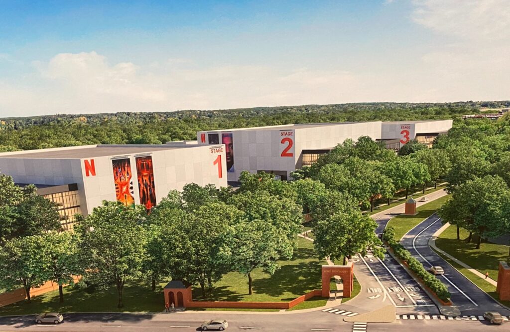 Architectural rendering of the planned Netflix Studios development at Fort Monmouth in Eatontown, NJ, with large numbered production stages, the Netflix logo, and lush tree-lined grounds