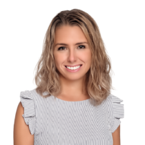 Professional headshot of Jessica Scarpino, featuring a smiling woman with wavy blonde hair wearing a light-colored patterned top with ruffled sleeves, set against a neutral studio background.
