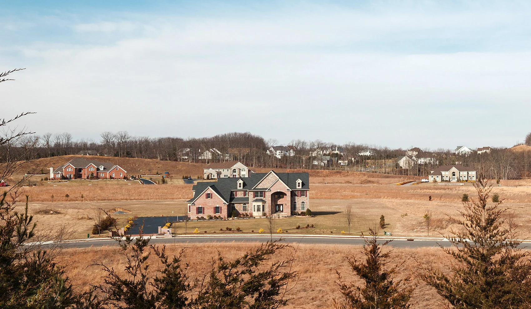 Aerial view of a large custom-built luxury home on a sprawling lot in Millstone Township, surrounded by open fields and trees.