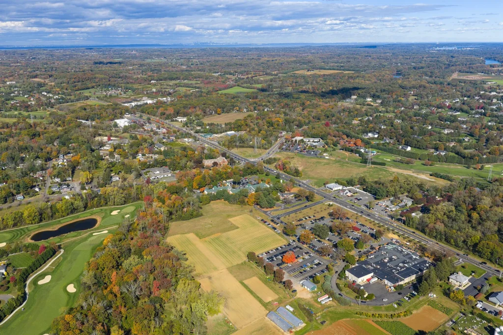 Wide aerial view of Marlboro or Holmdel, Monmouth County, NJ, with expansive open fields, a golf course, low-density residential neighborhoods, and colorful fall foliage stretching to the horizon