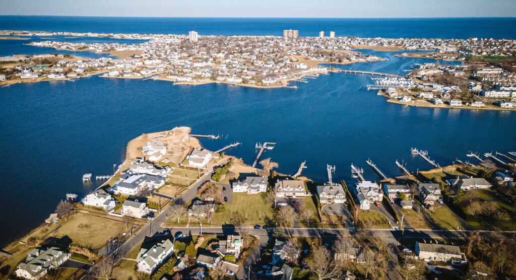 Aerial winter view of a narrow coastal peninsula in Monmouth County, NJ, with waterfront homes, private docks, and calm bay waters on both sides, representing Sea Bright, Monmouth Beach, and Oceanport