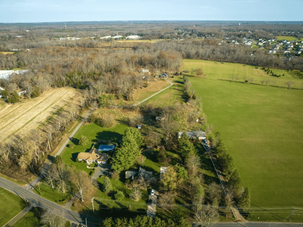 Aerial winter view of Freehold Township, NJ, with expansive open farmland, scattered rural homes nestled among bare trees, and flat terrain stretching across central Monmouth County